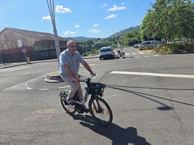 Gros plan sur un usager circulant sur un vélo à assistance électrique Vélo Fluo à Revin, montrant le panier avant et l'assistance électrique.