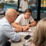 Participants échangeant autour d'une table, avec la bannière « Mobilité durable en entreprise » en arrière-plan.