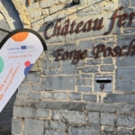 Panneau d’entrée du Château-ferme de Mâcon fixé sur un mur en pierre.