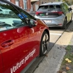 Voiture rouge et voiture grise garées côte à côte sur un parking.