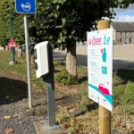 Panneau de signalisation et kakémono coloré installés en extérieur, devant des arbres.