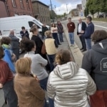 Groupe de participants debout en extérieur, écoutant des explications dans une rue.