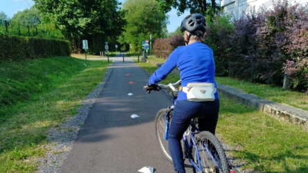 La cycliste casquée sur une piste cyclable balisée de plots.