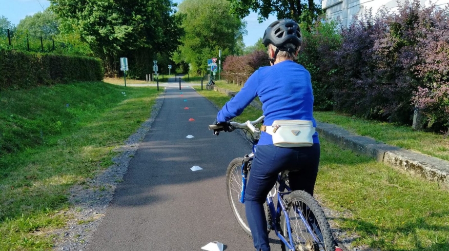 La cycliste casquée sur une piste cyclable balisée de plots.